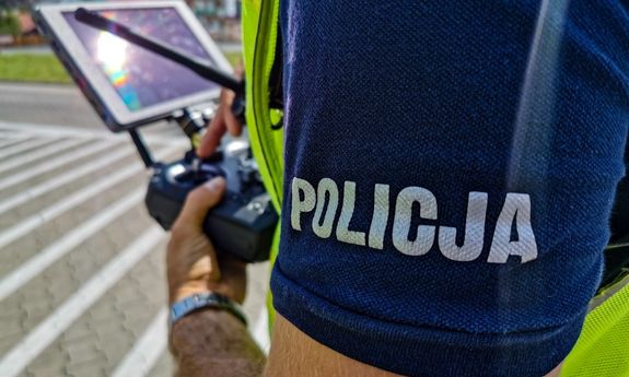 policjant trzyma w ręce sterownik do drona