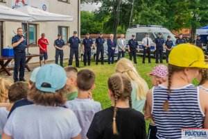 Grupa policjantów – zaproszonych gości oraz grupa dzieci stojąca podczas powitania uczestników akcji