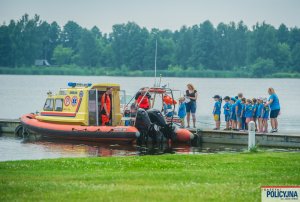 Grupa dzieci stojąca na pomoście przy Łodzi – Ambulansie Ratownictwa Wodnego