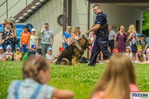 Przewodnik psa policyjnego podczas pokazu tresury i posłuszeństwa psa w tle grupy dzieci