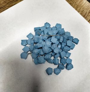 tabletki ecstasy koloru niebieskiego znajdujące się na kartce papieru