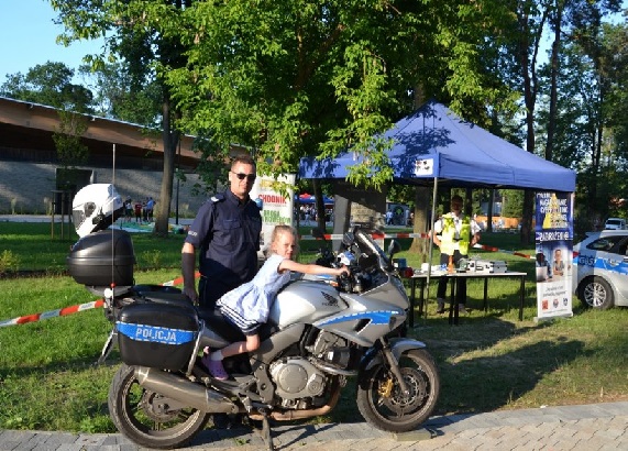 Policjant stojący obok motocykla wraz z chłopcem