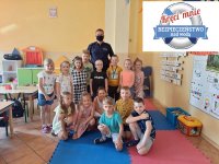 grupa dzieci wraz z policjantem stojących w szkolnej sali w górnym prawym rogu logo akcji koło ratunkowe z napisem kręci mnie bezpieczeństwo nad wodą