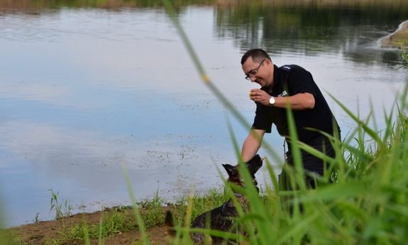 Umundurowany policjant z psem nad rzeką