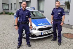dwaj policjanci stoją przy radiowozie