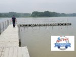 policjant odwrócony tyłem idzie pomostem nad zbiornikiem wodnym w prawym dolnym rogu umieszczone jest logo akcji koło ratunkowe na białym tle