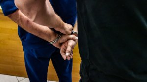 policjant kryminalny w cywilnych ubraniach zakłada kajdanki zatrzymanemu mężczyźnie