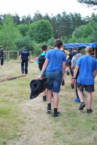 grupa uczestników obozu wraz z policjantem na leśnej polanie