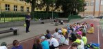 policjant na boisku szkolnym opowiada grupie dzieci o zasadach bezpieczeństwa