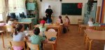 policjant w szkolnej sali opowiada o bezpieczeństwie grupie dzieci