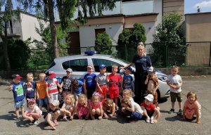 policjantka z grupą dzieci stoi obok radiowozu
