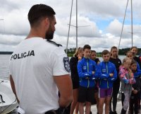 policjant z grupą dzieci obok zbiornika wodnego