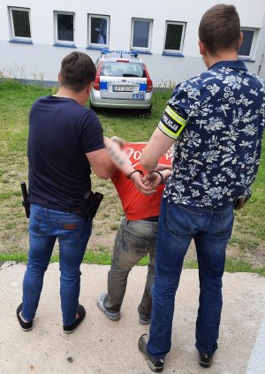 Policjanci prowadzą zatrzymanego mężczyznę