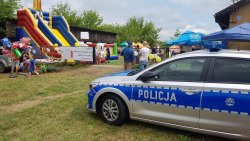 na pierwszym planie stoi radiowóz w oddali uczestnicy festynu i dmuchane zjeżdżalnie