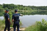 para policjantów kontroluje brzeg zbiornika wodnego
