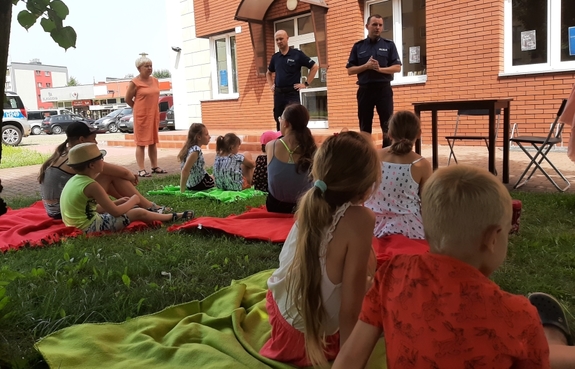 policjanci przed budynkiem rozmawiają z dziećmi o bezpieczeństwie