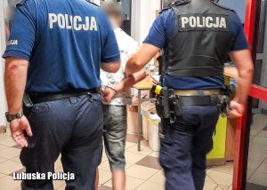 dwaj policjanci prowadzą zatrzymanego mężczyznę