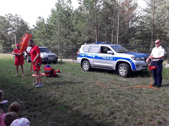 policjant z ratownikami wodnymi rozmawiają z dziećmi o bezpieczeństwie