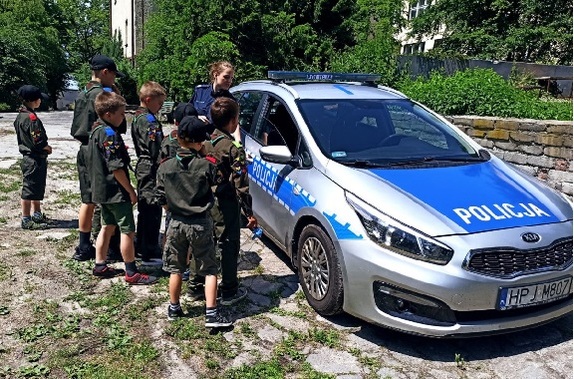 Policjantka stojąca obok radiowozu wraz z harcerzami