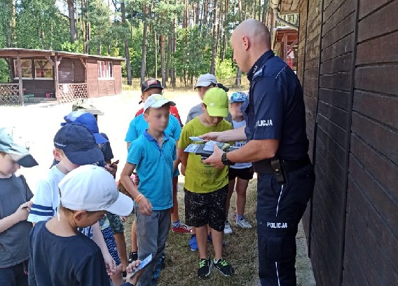 Policjant podczas wręczania dzieciom ulotek