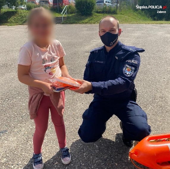 Policjant przekazujący dziewczynce gadżety