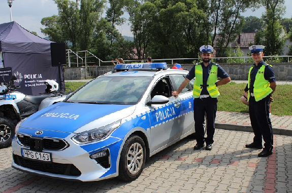 Policjanci stojący przy radiowozie policyjnym.