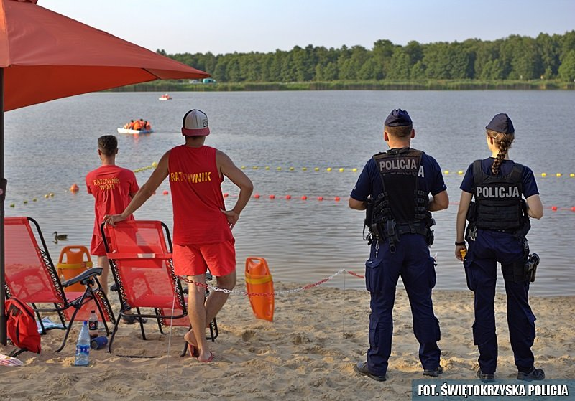 Policjanci wspólnie z ratownikami obserwują wodę.