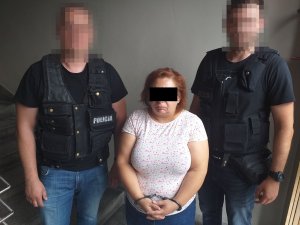 dwaj policjanci prowadzą zatrzymaną kobietę