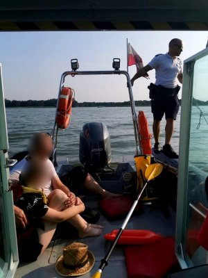 policjant i dwie uratowane osoby na łodzi policyjnej