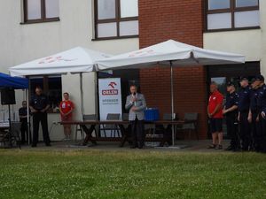 Na środku z mikrofonem w dłoni stoi Starosta Legionowski Sylwester Sokolnicki po prawej i lewej stronie stoją policjanci w mundurach oraz dwie osoby w czerwonych koszulkach WOPR.