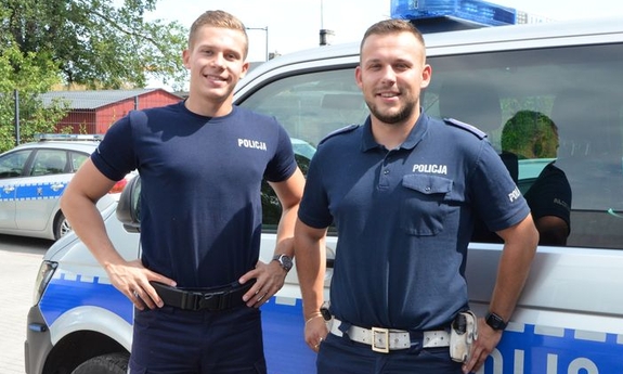 dwaj policjanci stoją przy radiowozie policyjnym