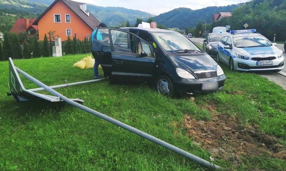 samochód obok radiowóz oznakowany oraz uszkodzony znak drogowy