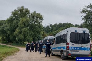 Policjanci uczestniczący w poszukiwaniach i radiowozy