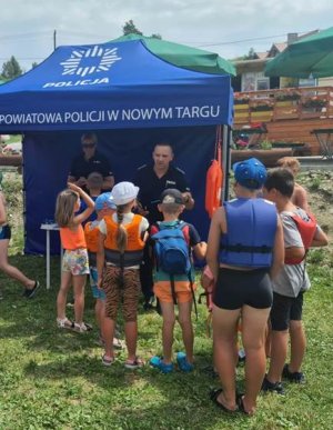 dwójka policjantów w namiocie obok stoi grupa dzieci