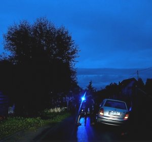 Zdjęcie w porze nocnej. Samochód osobowy marki Skoda. Obok niego na drodze widać zarys stojących osób
