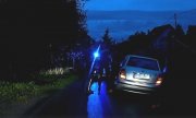 Zdjęcie w porze nocnej. Samochód osobowy marki Skoda. Obok niego na drodze widać zarys stojących osób