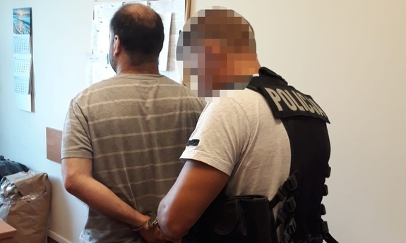 policjant rozkuwa z kajdanek zatrzymanego