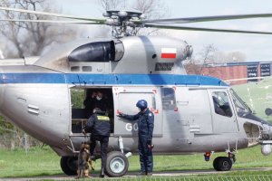 Przewodnik z psem wsiadają na pokład helikoptera, obok stoi członek załogi.