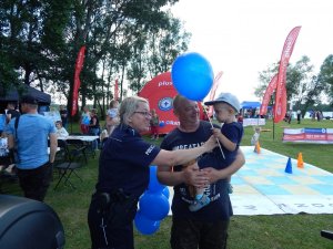 policjantka wręcza dziecku balon podczas festynu w plenerze