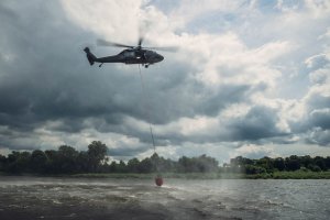 Śmigłowiec nabiera wodę do bambi bucket ze zbiornika wodnego.