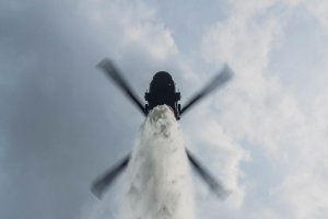 Helikopter zrucający wodę z bambi bucket - widok z dołu.