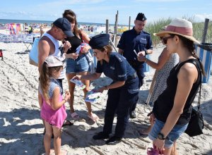 policjanci rozdaja ulotki przy plaży