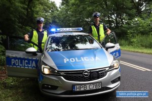 dwaj policjanci stoja przy radiowozie