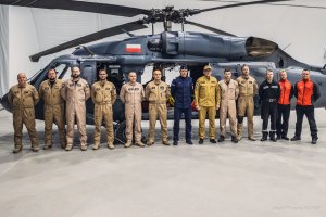 Grupowe zdjęcie policjantów i strażaków wyruszających do Turcji na tle śmigłowca S70i Black Hawk. W środku grupy zastępca Komendanta Głównego Policji nadinsp. Roman Kuster oraz zastępca Komendanta Głównego Państwowej Straży Pożarnej nadbryg. Krzysztof Hejduk.