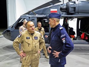 Rozmowa zastępcy Komendanta Głównego Policji nadinsp. Romana Kustera z naczelnikiem Zarządu Lotnictwa Policji insp. Robertem Sitkiem. W tle śmigłowiec S70i Black Hawk.