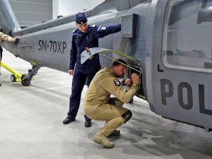 Wyprowadzanie śmigłowca S70i Black Hawk na płytę startową. Na zdjęciu członek załogi dokonujący ostatnich sprawdzeń aparatury w bocznym luku maszyny oraz zastępca Komendanta Głównego Policji nadinsp. Roman Kuster.