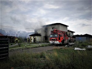 strażacy i wóz strażacki przy palącym się domu