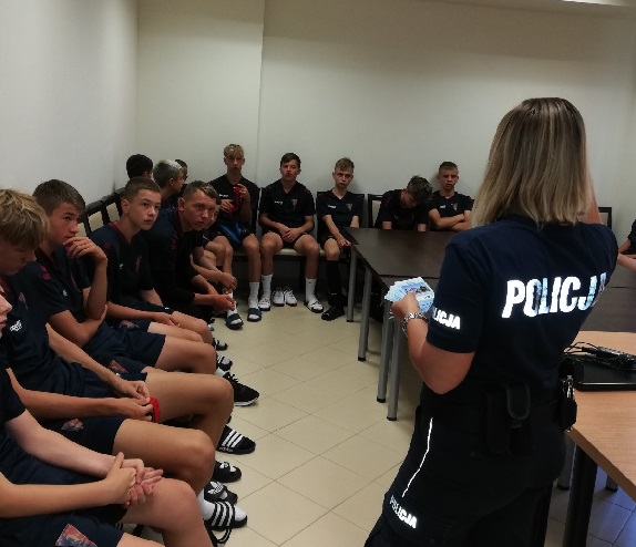 Policjantka podczas pogadanki profilaktycznej skierowanych do siedzącej wokół niej młodzieży