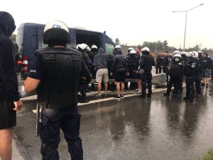 Policjanci z pododdziałów zwartych zabezpieczają zatrzymane do kontroli autokary na poboczu drogi ekspresowej.