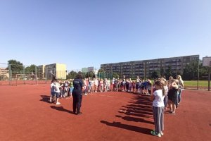 policjantka rozmawia z dziećmi o bezpieczeństwie na terenie boiska szkolnego
